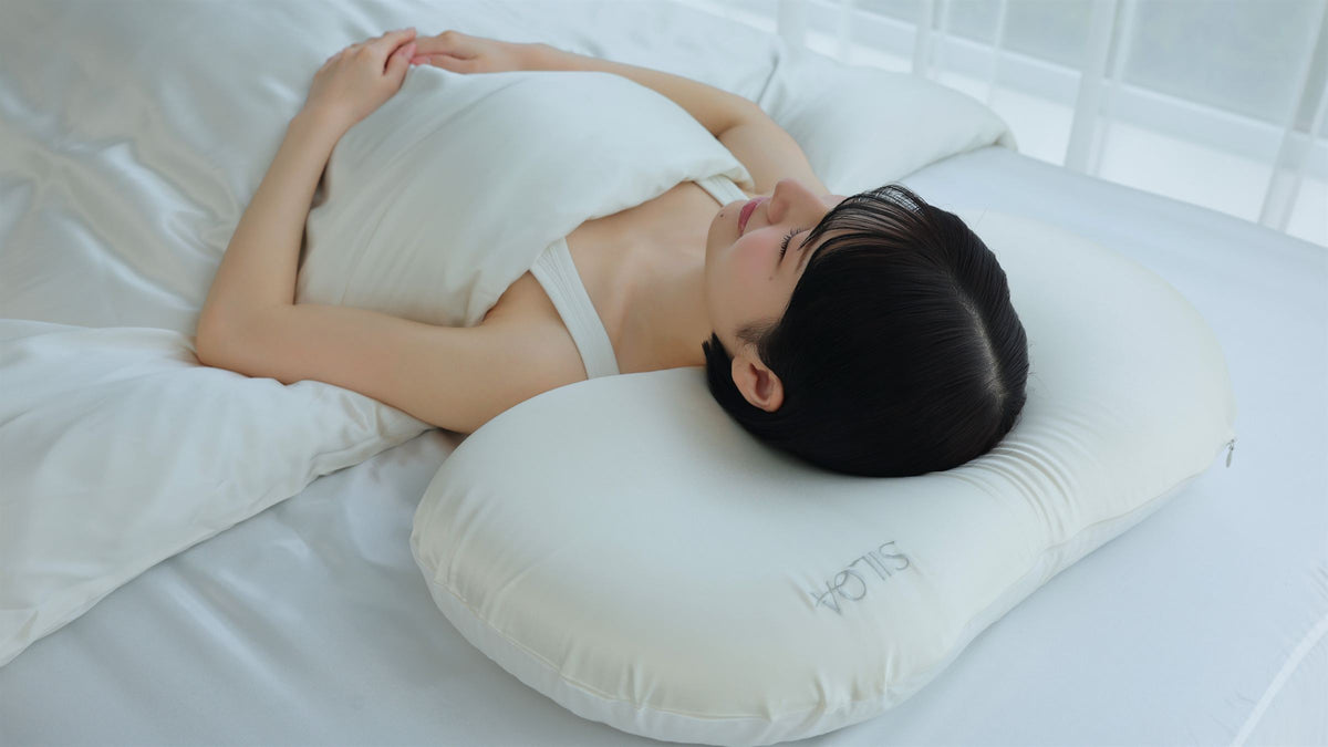 白いシルクセラムピローで眠る女性